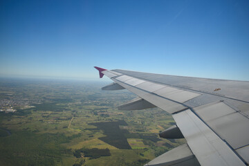 Fototapeta premium View from inside an airplane to the blue sky and green fields