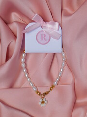 pulsera con etiqueta sobre tela rosada