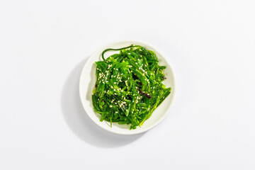 Chuka Seaweed Salad with sesame seeds isolated on white background. Trendy hard light, dark shadow
