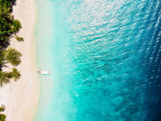 Beautiful tropical beach with crystal ocean and boat, aerial view.