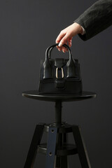 Top handle mini black bag made in textured, resistant leather. Studio shot on black background. © triocean