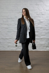 Studio portrait of fashionable girl in white button down shirt and striped oversized suit.