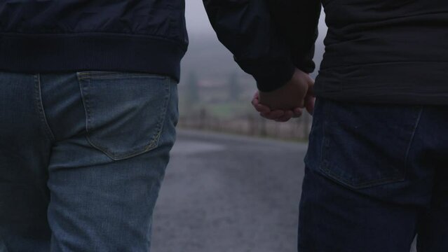 Two guys holding hands while walking