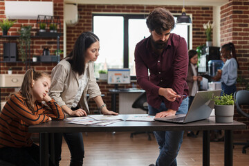 Working mother reviewing financial agency paperwork while daughter is bored. Young busy businesswoman analyzing company documentation while coworker pointing wrong accounting data.