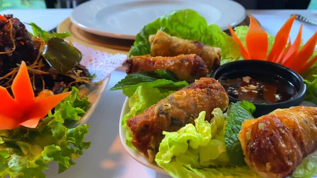 Traditional spring rolls with lettuce, carrots and crispy fried spicy beef strips in a thai restaurant, 4K shot