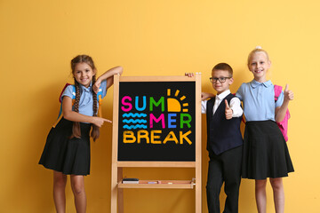 Happy school children near chalkboard with text SUMMER BREAK on color background