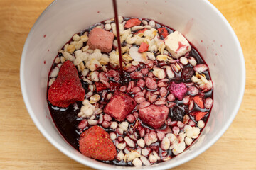 pouring mulberry juice to a bowl with nuts and dry fruits and melon seeds