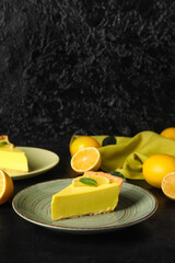 Plate with piece of tasty lemon pie and fresh fruits on black background