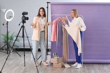 Young female fashion bloggers with trendy clothes recording video in studio