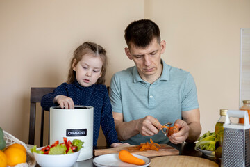 Girl throws vegetable peels into a compost bin. Dad cooks a vegetarian lunch with his daughter.