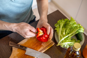 Man cuts vegetables in the kitchen to prepare a vegetarian dish. Family lifestyle