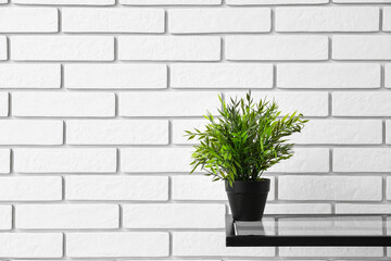 Table with houseplant near white brick wall