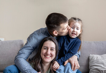 Fototapeta na wymiar Lifestyle family. Mom dad and daughter are sitting on the couch and hugging.