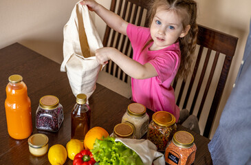 Dad and his daughter are pulling food out of the bag. Purchases from the store. Reusable package.
