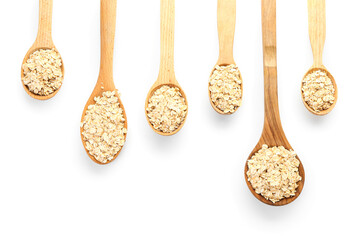 Spoons with raw oatmeal flakes on white background