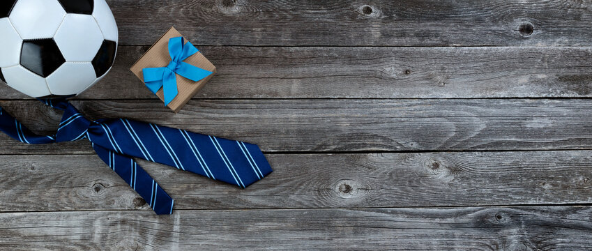 Blue tie, soccer ball and giftbox on a vintage wood table for Fathers Day gifts