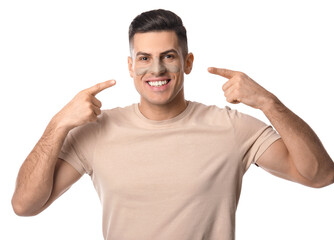 Handsome man pointing at applied clay mask on white background