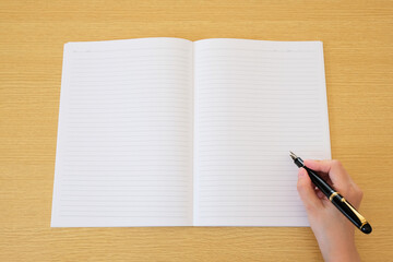 白紙のノートと万年筆ペンを握った手