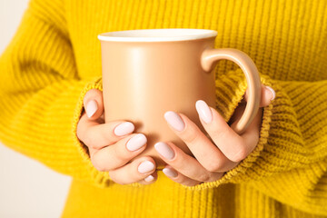 Woman in warm sweater with stylish manicure and cup, closeup