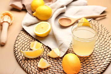 Cut lemons and glass of juice on color wooden background