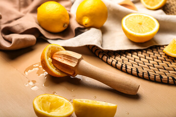 Cut lemons and juicer on color wooden background