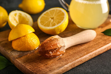 Wooden board with juicer and ripe lemons on table, closeup