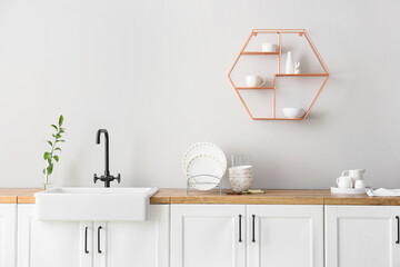 Counters with sink and dinnerware near light wall