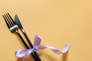 Cutlery with ribbon on color background