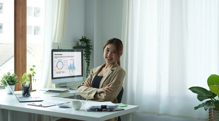 Portrait of confident young entrepreneur sitting at modern workplace and smiling to camera.