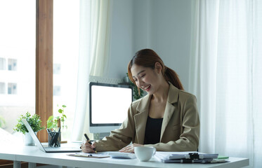 Young Asian businesswoman taking notes using a tablet at the modern office.
