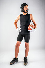 Youth male 7-on-7 football player standing with hand on hip while cradling the ball