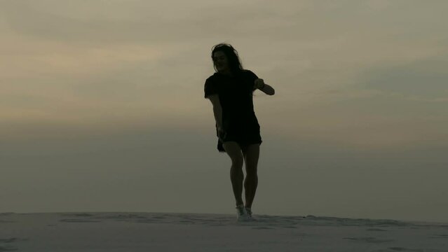 Silhouette of a girl dancing on the sand 4K. Healthy lifestyle. Happy free concept.