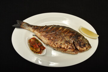 Roasted fish with lemon slices and  spicy sauce,dorada