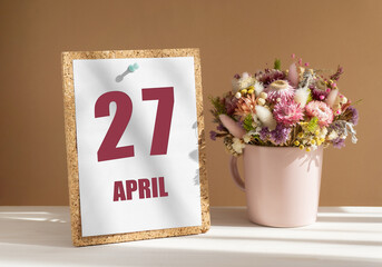 April 27. 27th day of month, calendar date.Bouquet of dead wood in pink mug on desktop.Cork board with calendar sheet on white-beige background. Concept of day of year, time planner, spring month