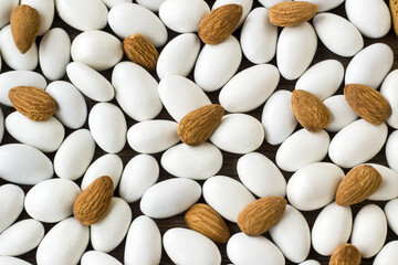 Traditional, white, chocolate covered candies with almonds nuts on wooden surface,fulled frame