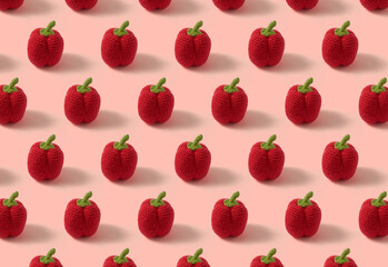 Pattern of red peppers knitted with wool. Handmade crochet bell peppers on pastel pink background. Composition of peppers. Amigurumi pepper. top view