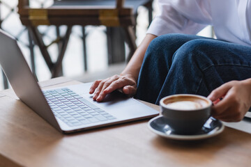 Closeup image of a woman working on laptop computer and drinking coffee