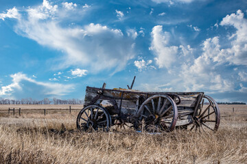 Fototapeta na wymiar Blue sky over an abandoned horse-drawn cart on the prairies in Saskatchewan, Canada