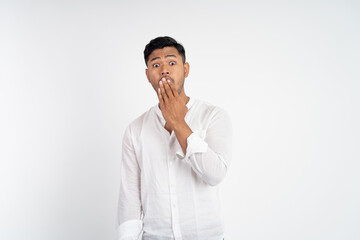 surprised young man with bulging eyes and hands covering mouth standing on isolated background