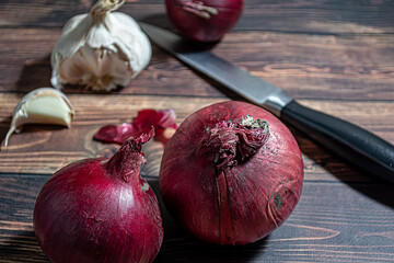 Fresh garlic bulbs and a garlic press on an old wooden board and a burlap backing.