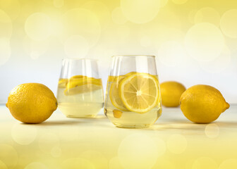 Two glasses with lemonade and sliced lemon on a white table. National Lemonade Day concept.