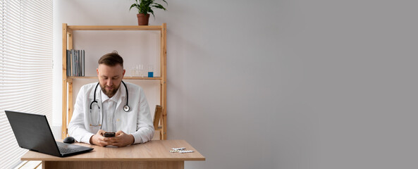 close-up portrait of a doctor he uses a mobile smartphone, works on a laptop in a medical office in a hospital, EHR electronic medical record system, cloud storage technology concept.