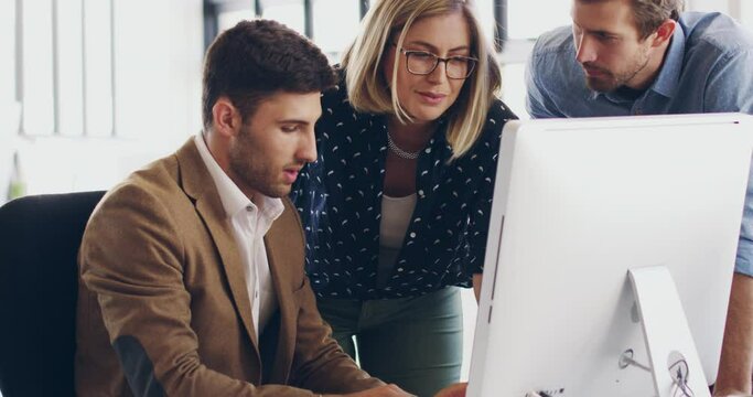 Some teamwork to get things done. Beautiful young business woman and handsome young business man gathered around another male colleague's desk in the office, talking about work, strategy and ideas