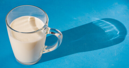 Glass mug of fresh milk on a blue background. Repeating seamless pattern