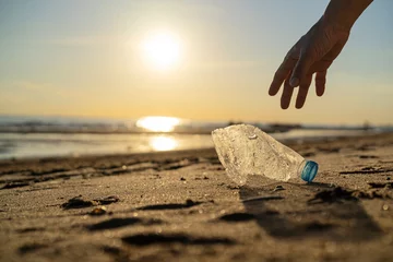 Zelfklevend Fotobehang Volunteer man and plastic bottle, clean up day, collecting waste on sea beach © jittawit.21