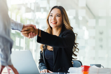 Portrait young Asian woman interviewer and interviewee shaking hands for a job interview .Business people handshake in modern office. Greeting deal concept © Phushutter