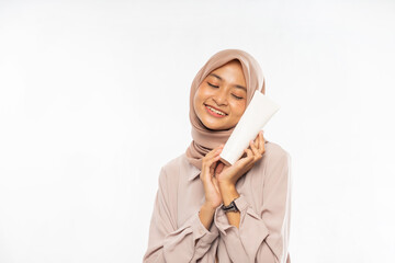 Muslim asian Beauty portrait. A beautiful girl with clean skin holds a white template tube in her hands. white background.