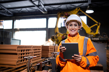 Portrait of production line female worker holding tablet computer and checking quality of the clay bricks in manufacturing factory.