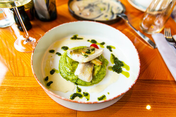 Baked zander fillet with herbs, combined with mashed potatoes with pesto. Garnished with wine sauce
