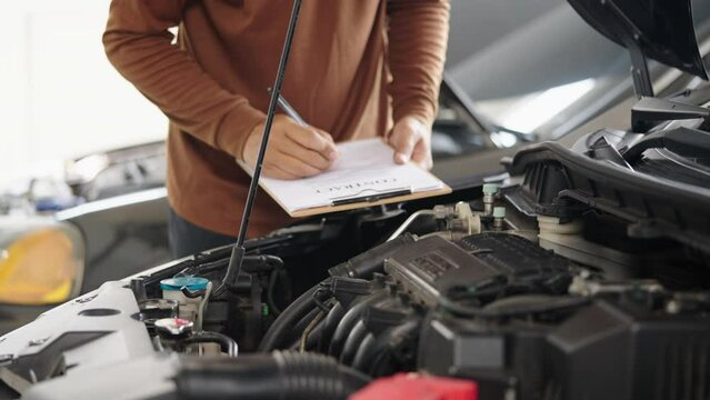 Photo of car mechanic repairs a car engine in his repair shop.